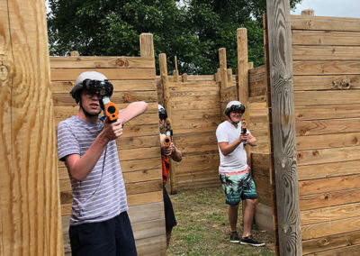 3 jeunes cachés jouant au laser game